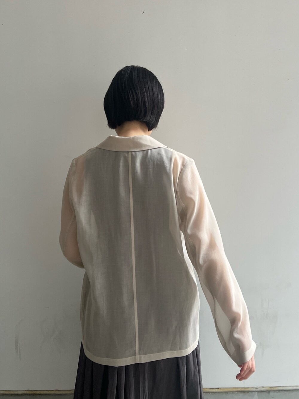 ブラック系のハンドバッグ、グレー系のワンピース、ホワイト系のテーラードジャケットを着用したレディースの春コーディネートの4枚目の写真