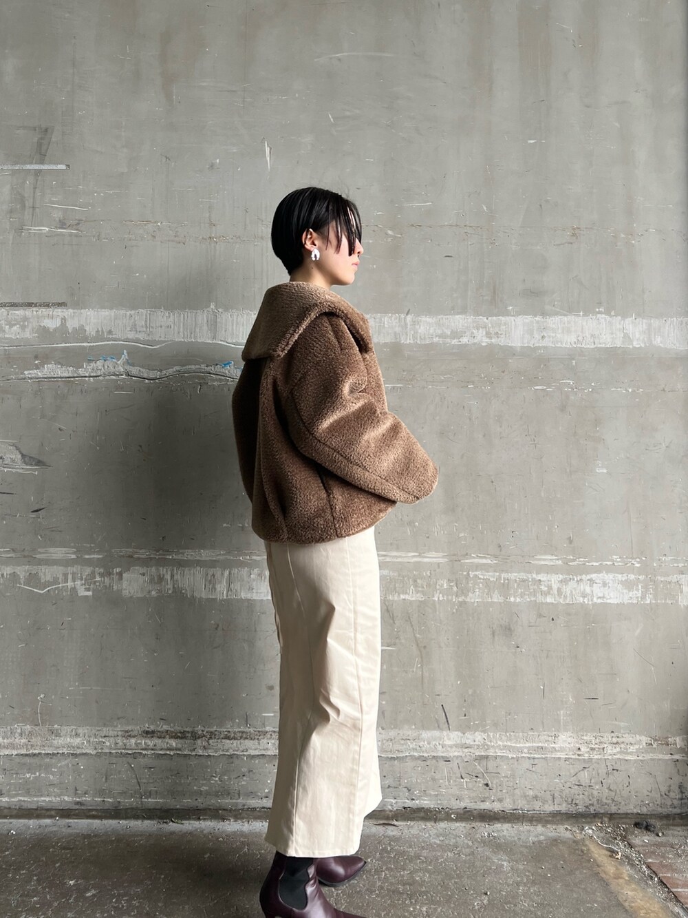 レッド系のブーツ、ホワイト系のスカート、ブラウン系のブルゾンを着用したレディースの冬コーディネートの2枚目の写真