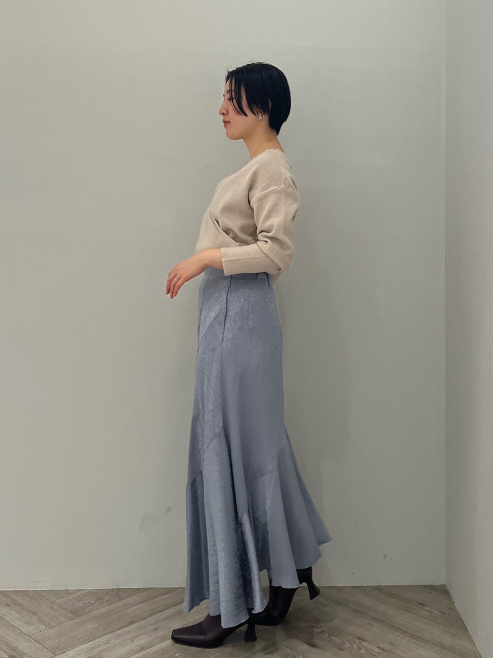 レッド系のブーツ、ブルー系のスカート、グレー系のニット/セーターを着用したレディースの冬コーディネートの2枚目の写真