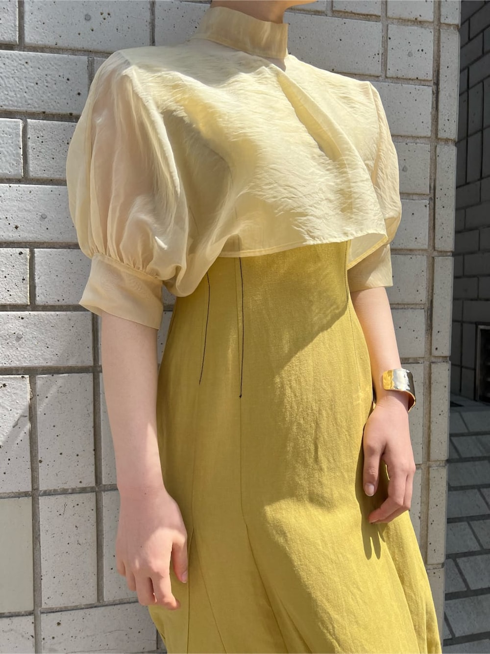 その他のパンプス、イエロー系のワンピース、ゴールド系のバングル/リストバンドを着用したレディースの春コーディネートの3枚目の写真