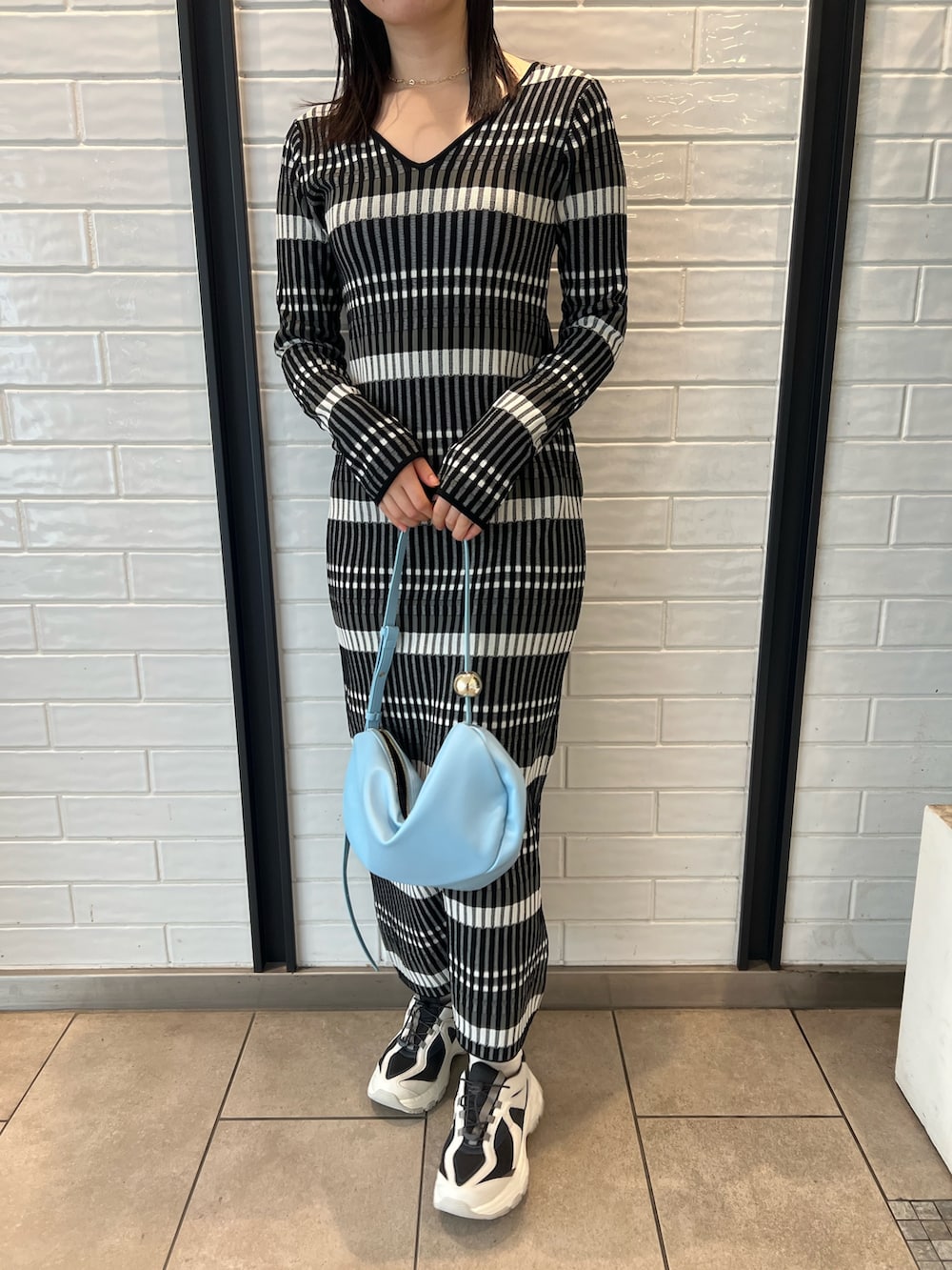 ブルー系のショルダーバッグ、ブラック系のワンピース、グレー系のスニーカーを着用したレディースの冬コーディネートの6枚目の写真