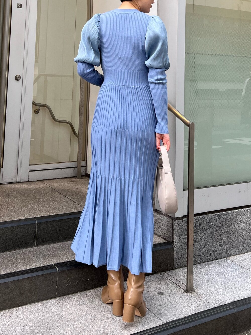 ベージュ系のブーツ、ホワイト系のハンドバッグ、ホワイト系のノーカラーコートを着用したレディースの冬コーディネートの6枚目の写真