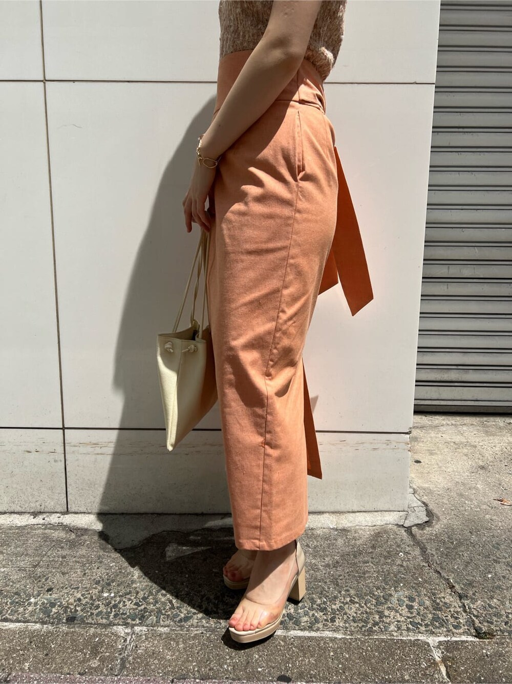 ホワイト系のハンドバッグ、オレンジ系のスカート、その他のパンプスを着用したレディースの春コーディネートの9枚目の写真