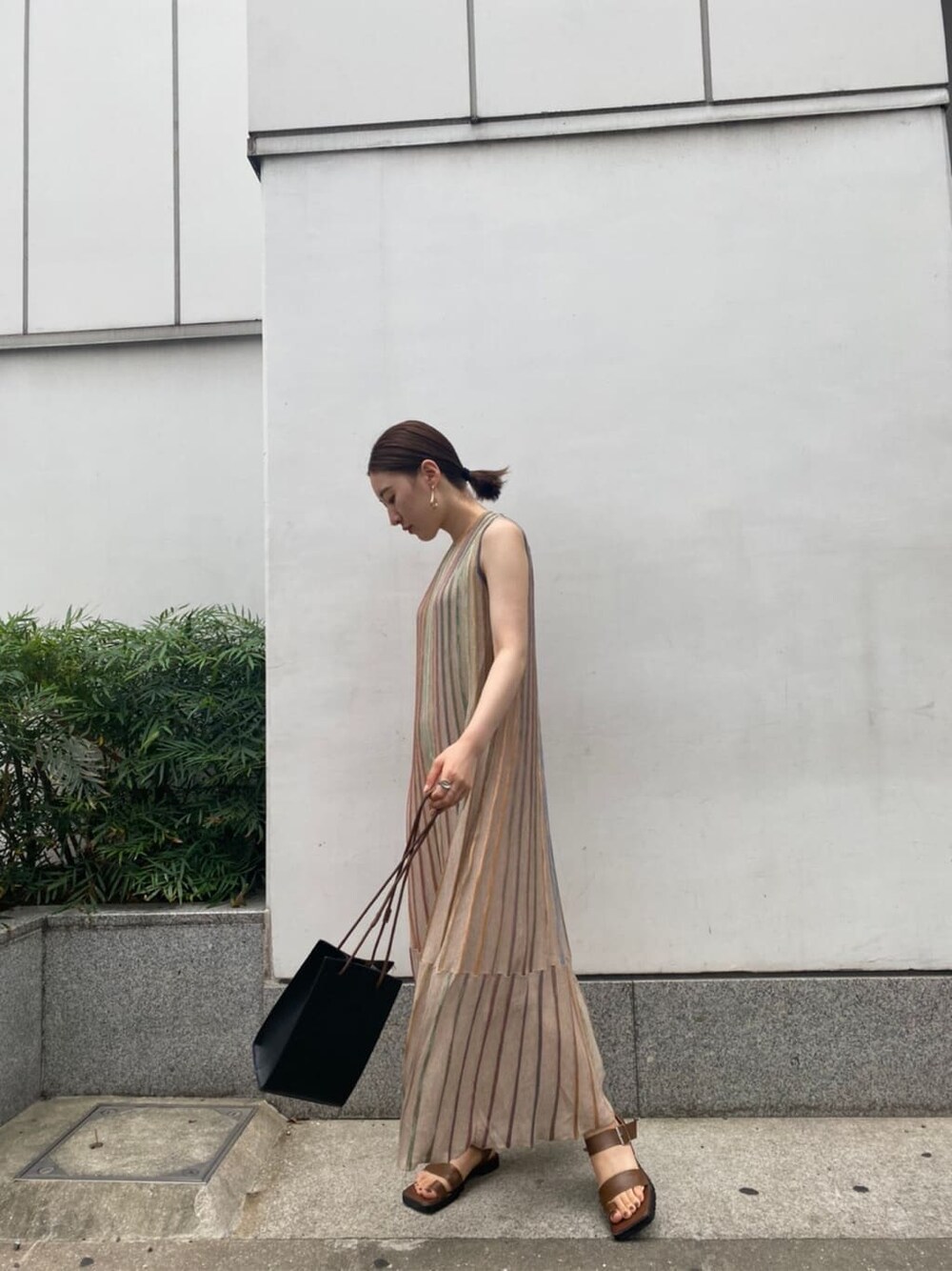 ブラック系のハンドバッグ、ブラウン系のサンダル、ベージュ系のワンピースを着用したレディースの夏コーディネートの3枚目の写真