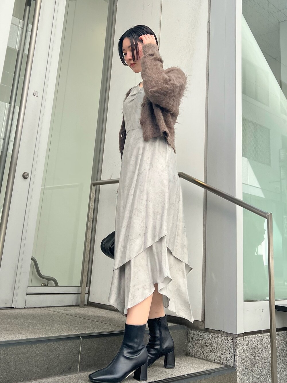 グレー系のカーディガン/ボレロ、グレー系のワンピース、ブラック系のブーツを着用したレディースの秋コーディネートの2枚目の写真