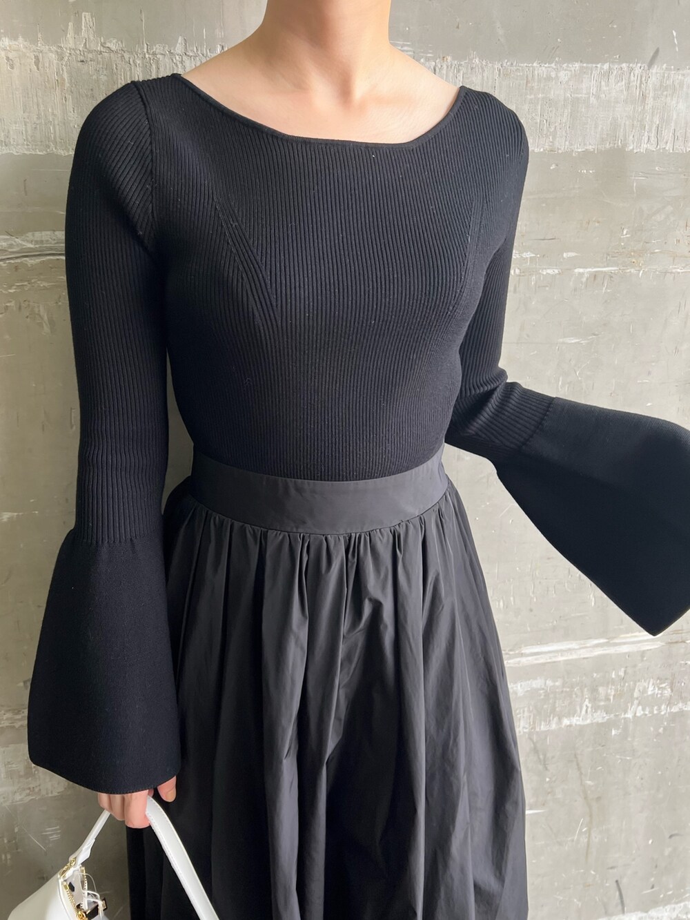 ホワイト系のハンドバッグ、ブラック系のワンピース、ブラック系のパンプスを着用したレディースの秋コーディネートの5枚目の写真