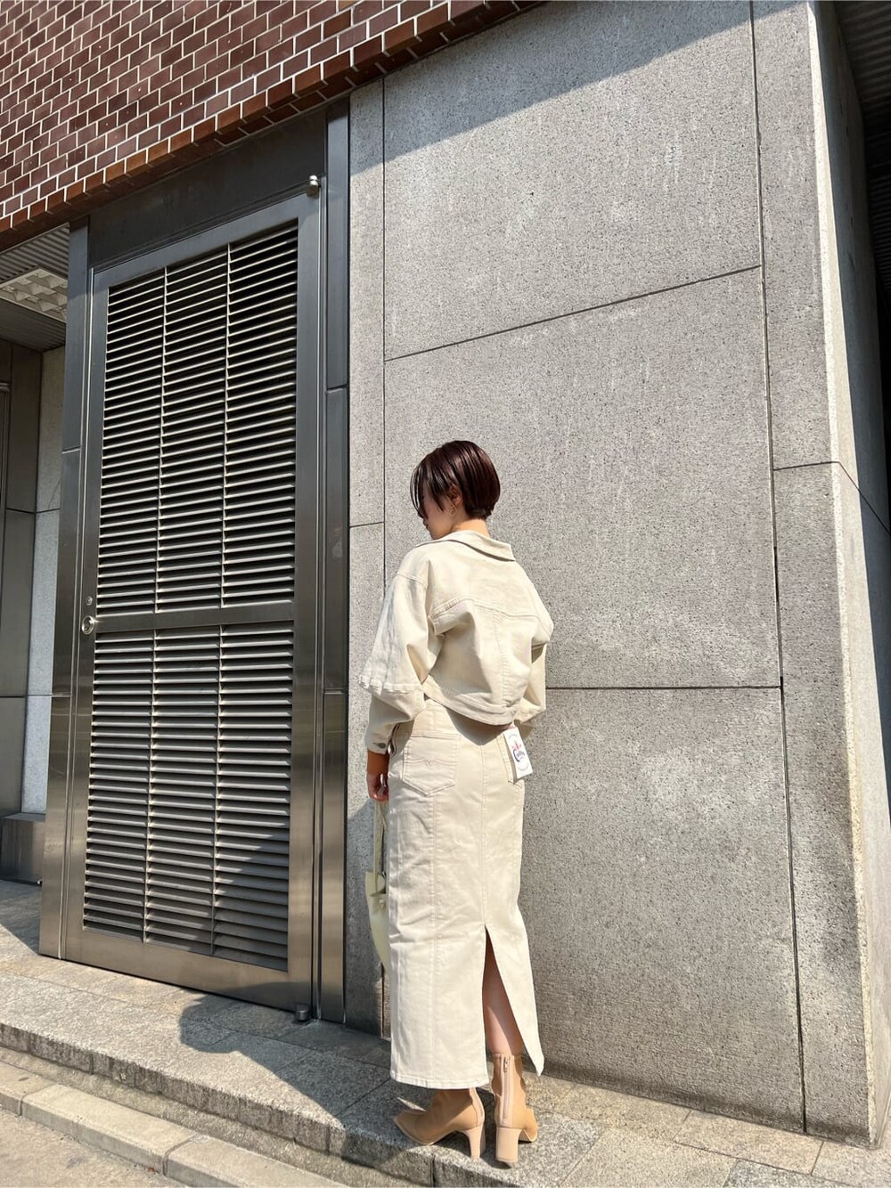 ホワイト系のハンドバッグ、ホワイト系のブルゾン、ホワイト系のスカートを着用したレディースの春コーディネートの3枚目の写真