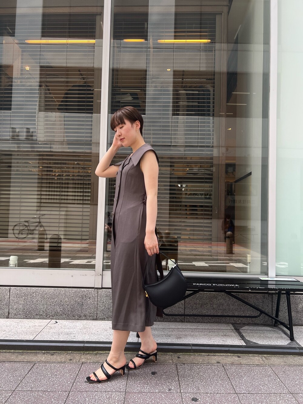 グレー系のワンピース、ブラック系のサンダル、ブラック系のハンドバッグを着用したレディースの夏コーディネートの2枚目の写真