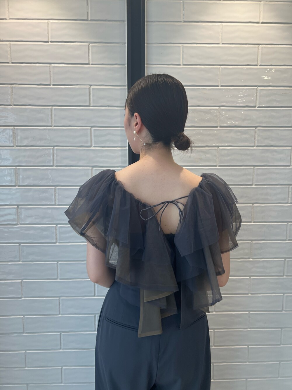 ゴールド系のハンドバッグ、ゴールド系のパンプス、グレー系のパンツドレスを着用したレディースの夏コーディネートの6枚目の写真