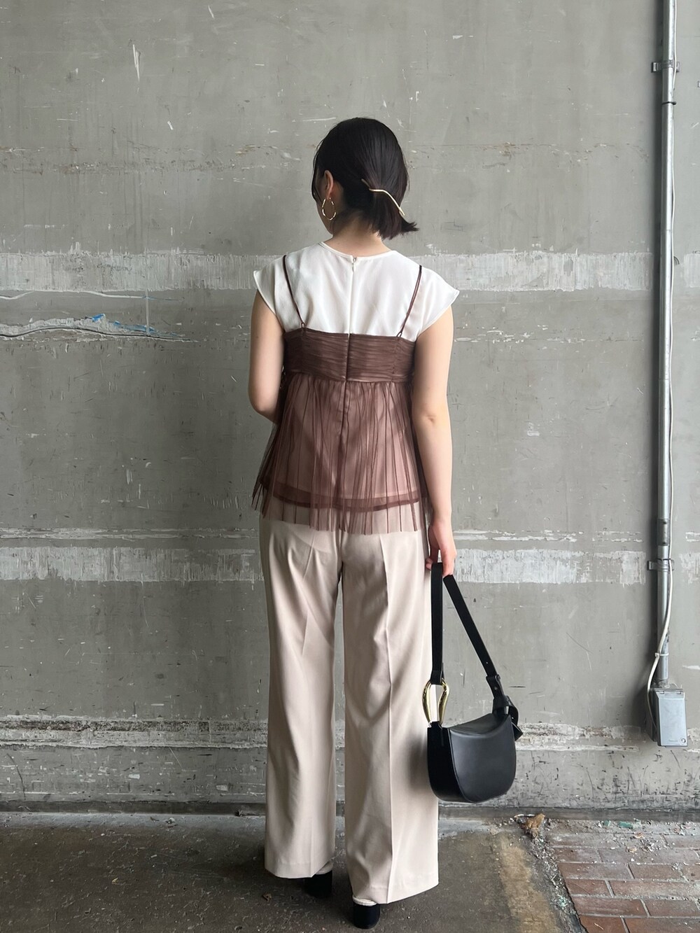 ブラック系のサンダル、ブラック系のショルダーバッグ、ホワイト系のスラックスを着用したレディースの夏コーディネートの2枚目の写真