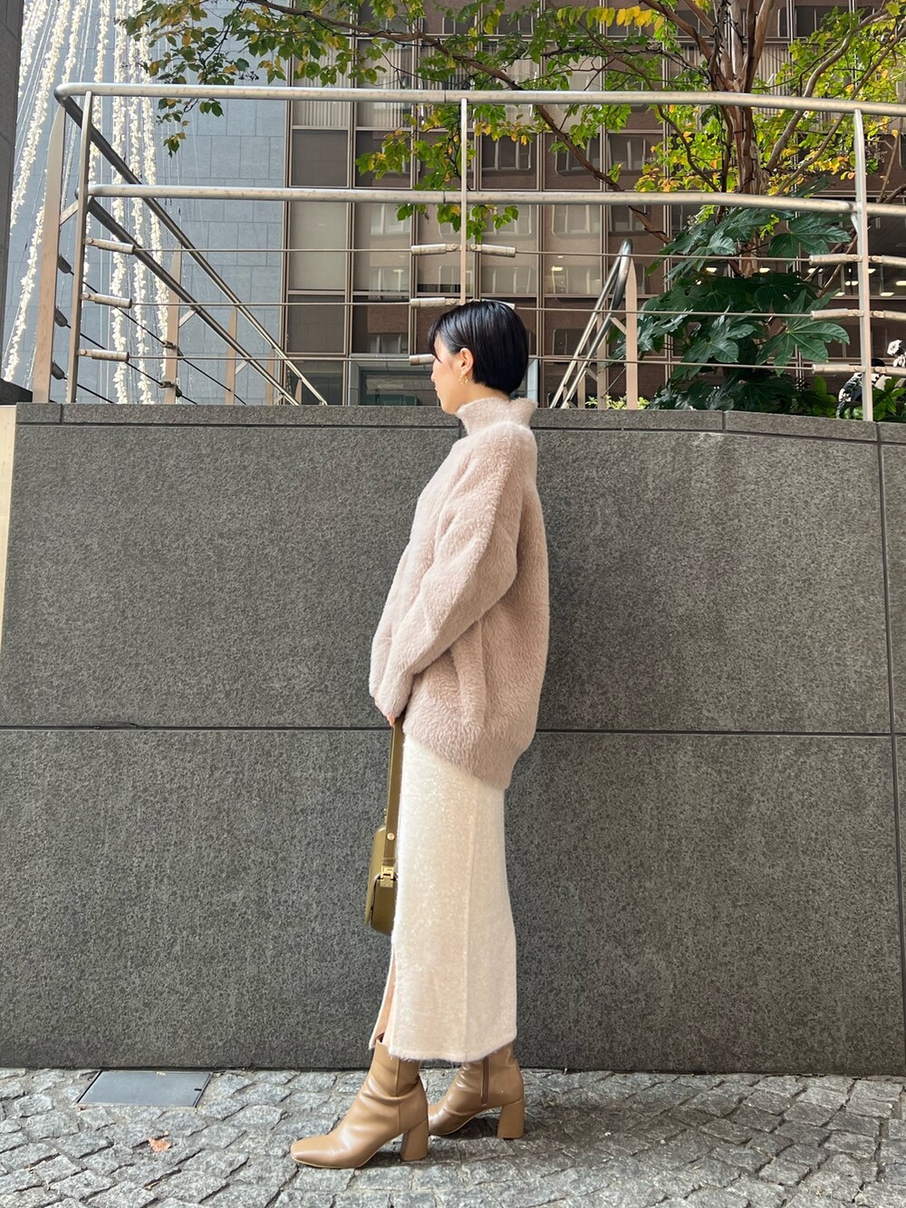 ブラウン系のショルダーバッグ、ブラウン系のニット/セーター、ベージュ系のブーツを着用したレディースの冬コーディネートの2枚目の写真