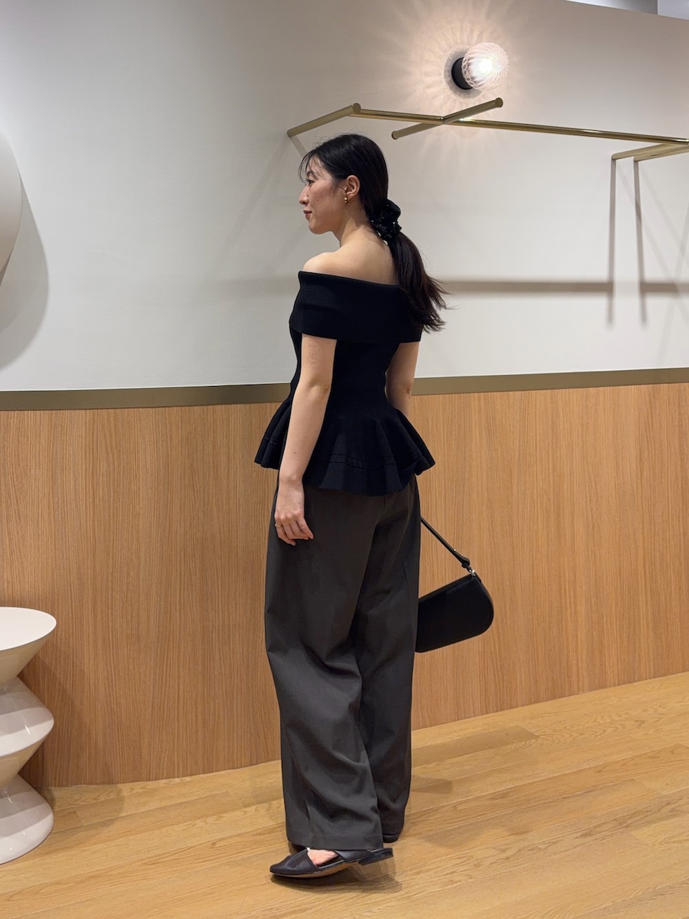 グレー系のその他パンツ、ブラック系のニット/セーター、ブラウン系のサンダルを着用したレディースの春コーディネートの2枚目の写真