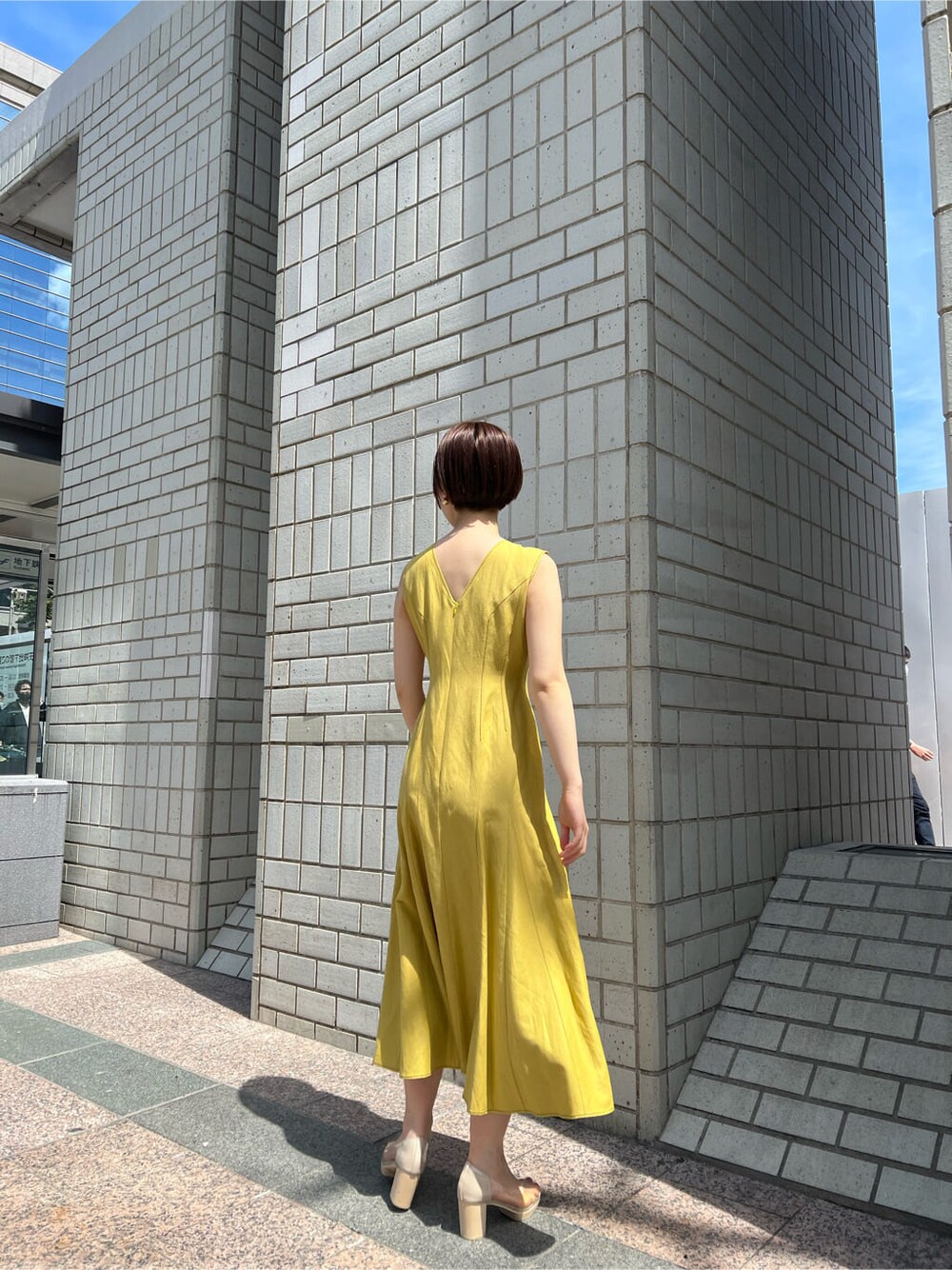 その他のパンプス、イエロー系のワンピース、ゴールド系のバングル/リストバンドを着用したレディースの春コーディネートの8枚目の写真