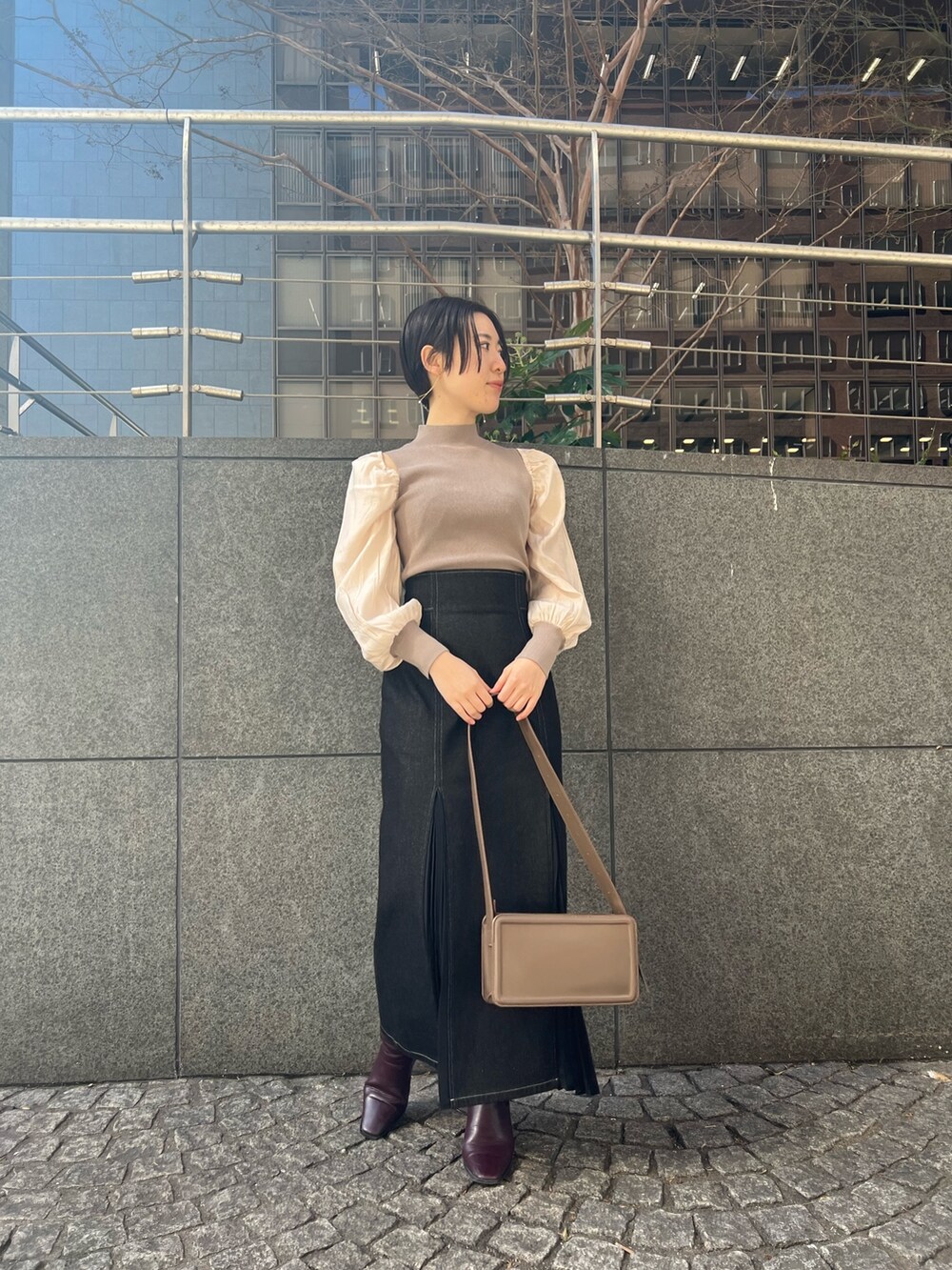 ブラック系のデニムスカート、ベージュ系のショルダーバッグ、レッド系のブーツを着用したレディースの冬コーディネートの6枚目の写真