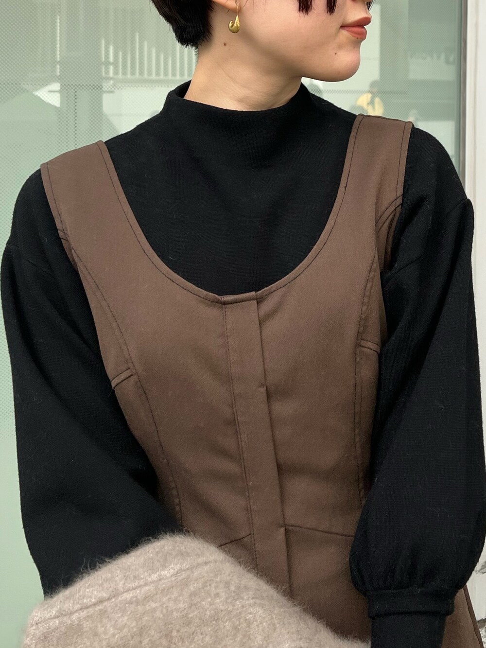 ブラック系のハンドバッグ、ベージュ系のブーツ、ベージュ系のカーディガン/ボレロを着用したレディースの秋コーディネートの4枚目の写真