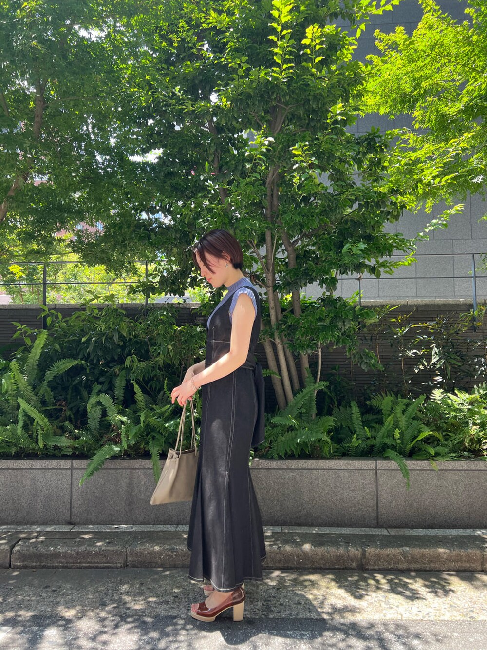 ブルー系のニット/セーター、ブラック系のワンピース、ベージュ系のハンドバッグを着用したレディースの夏コーディネートの2枚目の写真