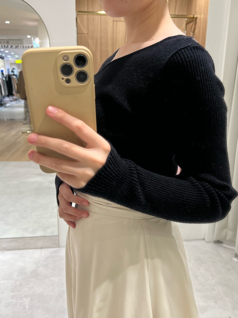 ホワイト系のスカート、ブラック系のニット/セーター、ベージュ系のブーツを着用したレディースの秋コーディネートの3枚目の写真