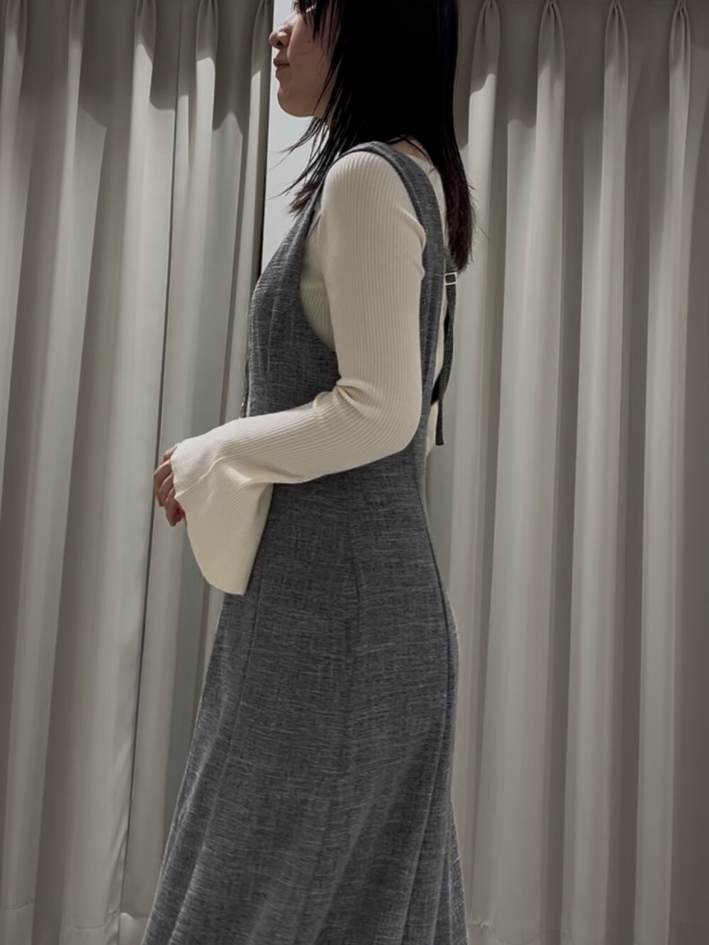 ホワイト系のニット/セーター、グレー系のジャンパースカート、ブラック系のサンダルを着用したレディースの春コーディネートの5枚目の写真