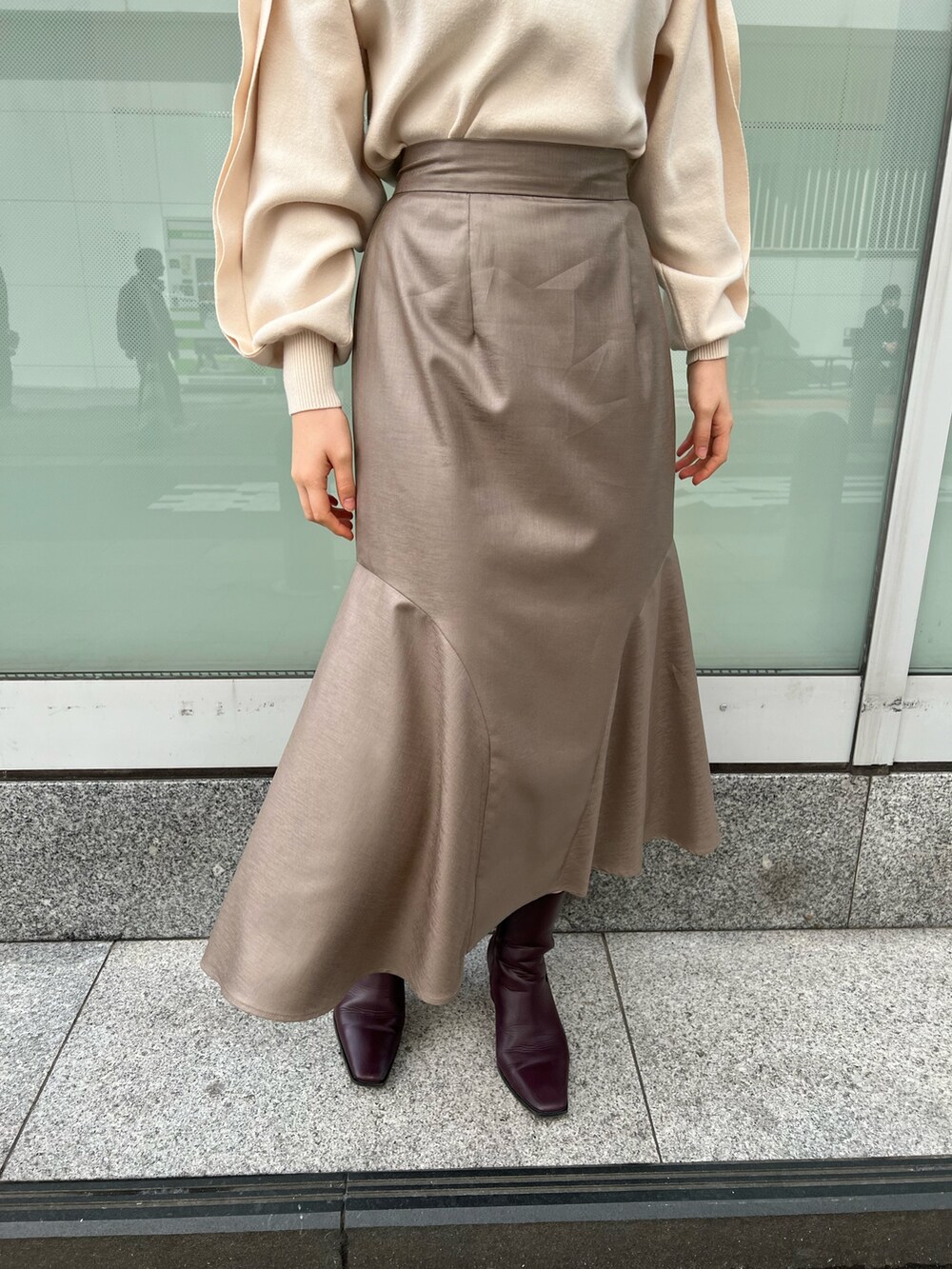 レッド系のブーツ、ベージュ系のスカート、ホワイト系のニット/セーターを着用したレディースの冬コーディネートの7枚目の写真