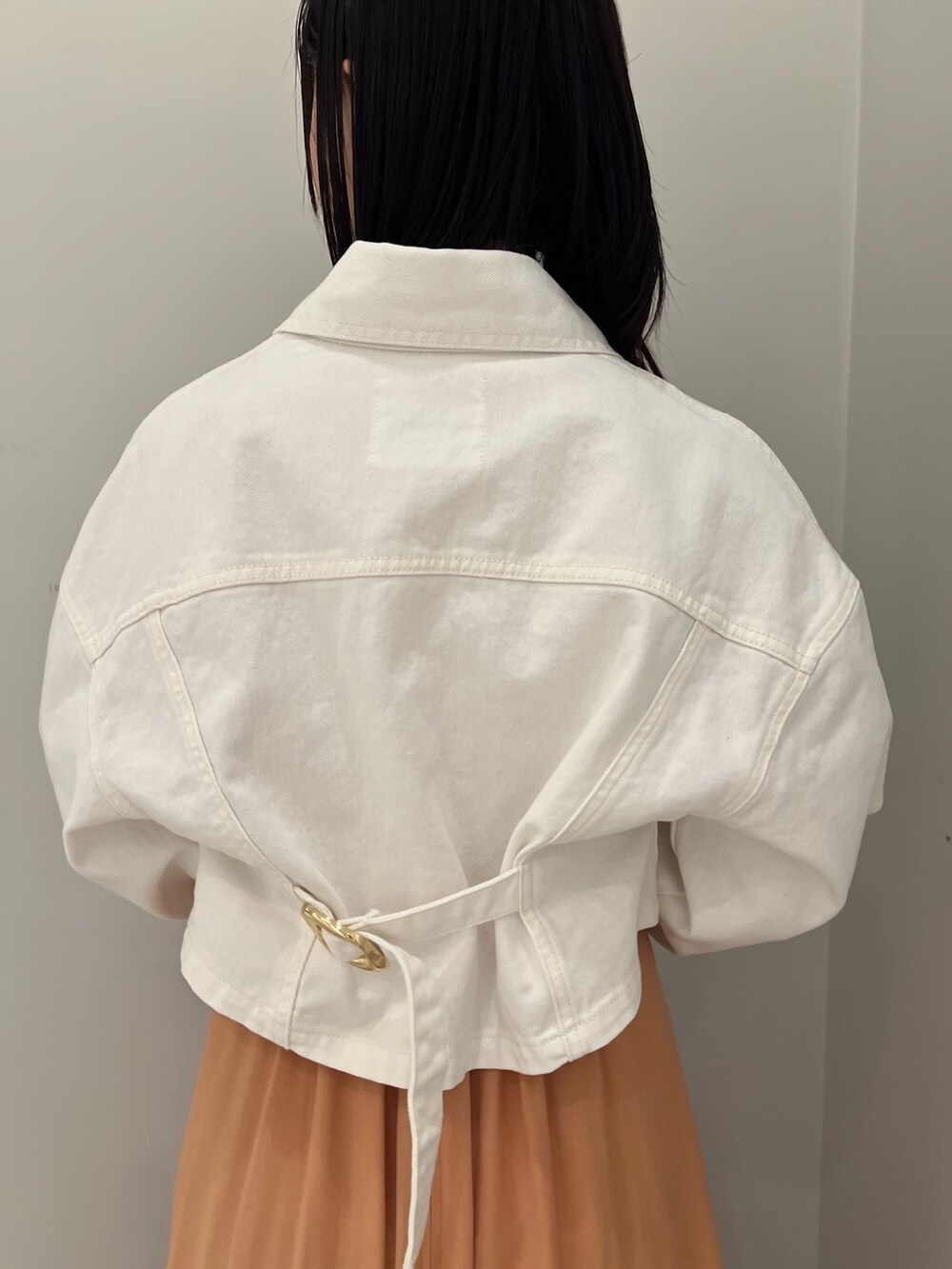 ホワイト系のサンダル、オレンジ系のワンピース、ホワイト系のデニムジャケットを着用したレディースの春コーディネートの5枚目の写真