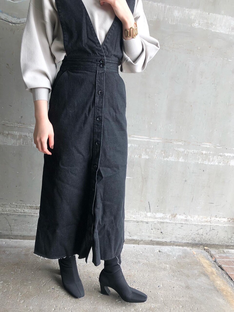 ブルー系のスカート、グレー系のニット/セーター、ゴールド系のピアス（両耳用）を着用したレディースの冬コーディネートの4枚目の写真