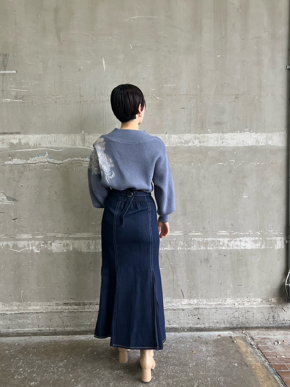 ベージュ系のブーツ、ブルー系のスカート、ホワイト系のダウンジャケット/コートを着用したレディースの冬コーディネートの7枚目の写真