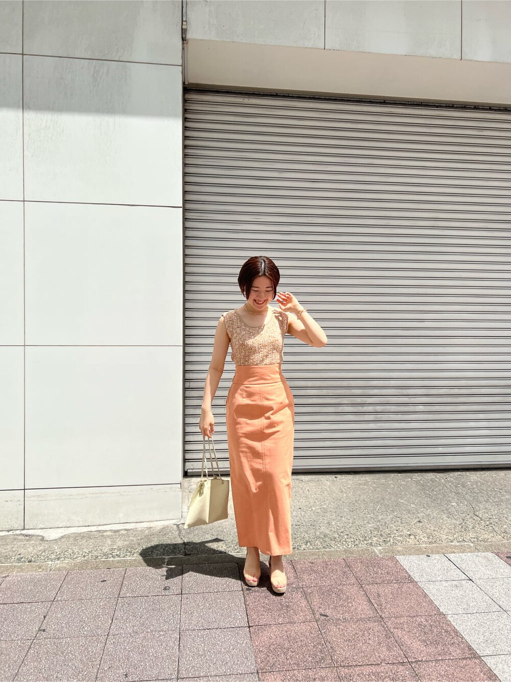 ホワイト系のハンドバッグ、オレンジ系のスカート、その他のパンプスを着用したレディースの春コーディネートの4枚目の写真