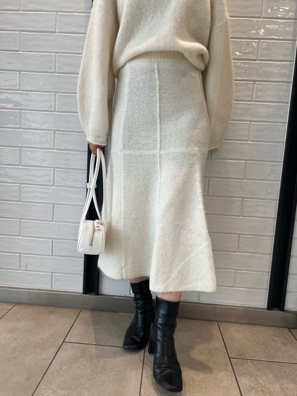 ホワイト系のスカート、ホワイト系のニット/セーター、ホワイト系のショルダーバッグを着用したレディースの秋コーディネートの5枚目の写真