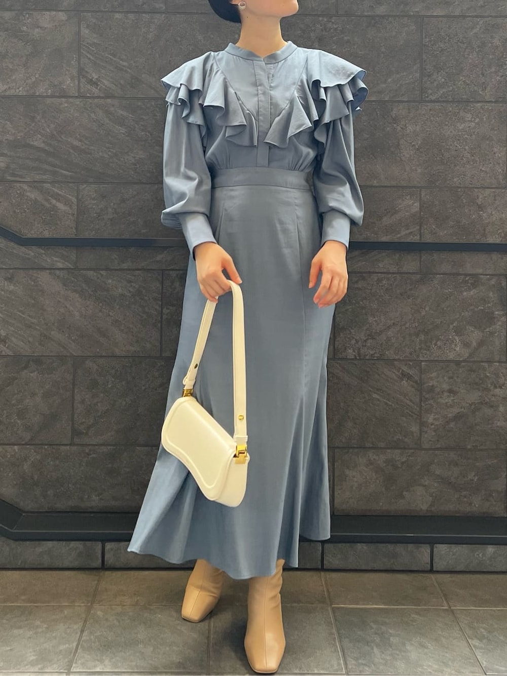 ベージュ系のブーツ、ブルー系のワンピース、ホワイト系のショルダーバッグを着用したレディースの夏コーディネートの2枚目の写真