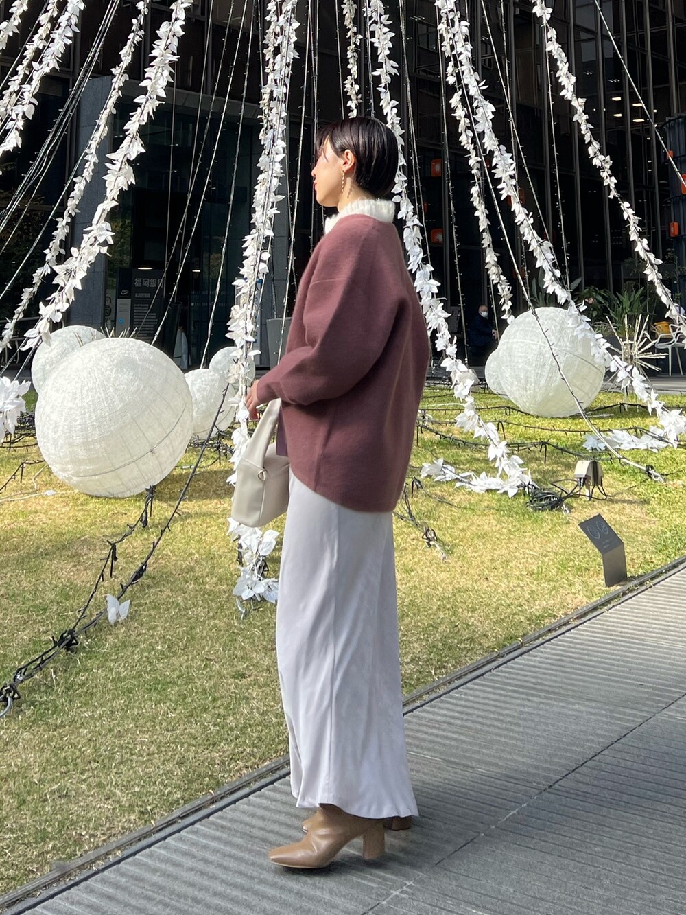 ホワイト系のスカート、ホワイト系のハンドバッグ、ピンク系のカーディガン/ボレロを着用したレディースの冬コーディネートの2枚目の写真