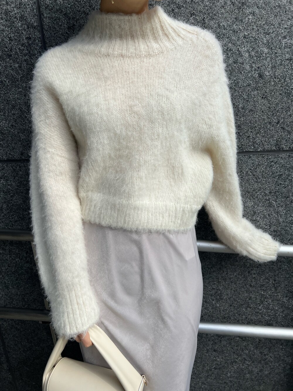 ホワイト系のスカート、ホワイト系のハンドバッグ、ピンク系のカーディガン/ボレロを着用したレディースの冬コーディネートの7枚目の写真