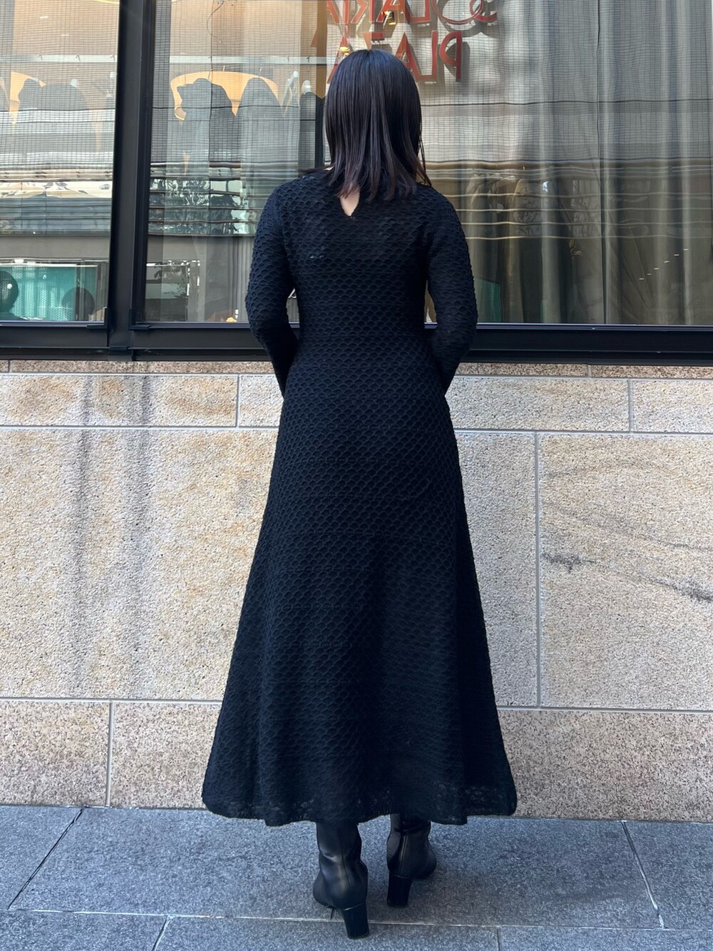 ブラック系のブーツ、ブラック系のワンピース、ホワイト系のショルダーバッグを着用したレディースの秋コーディネートの5枚目の写真