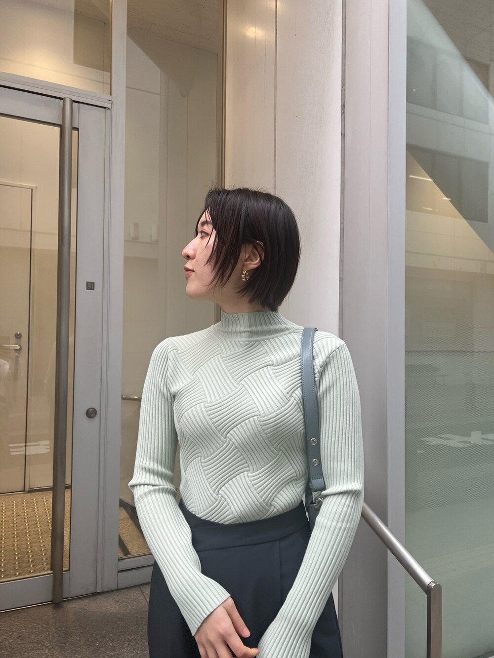 ブルー系のショルダーバッグ、グレー系のスラックス、グリーン系のニット/セーターを着用したレディースの冬コーディネートの4枚目の写真