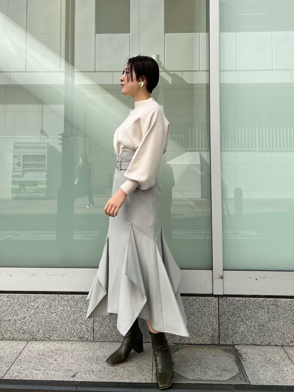 ベージュ系のブーツ、グリーン系のスカート、ホワイト系のニット/セーターを着用したレディースの冬コーディネートの2枚目の写真