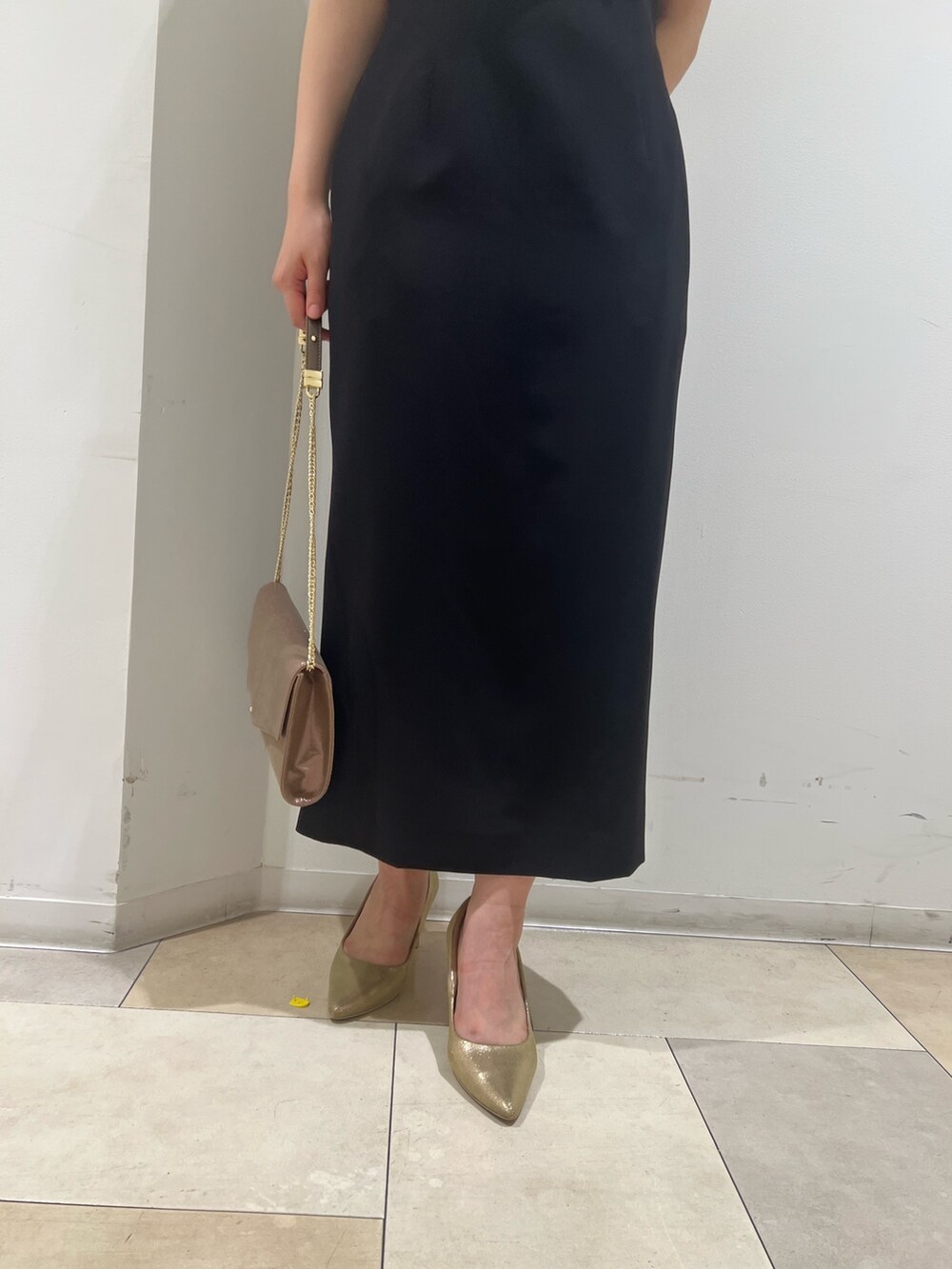 ゴールド系のパンプス、ゴールド系のハンドバッグ、ブラック系のドレスを着用したレディースの夏コーディネートの7枚目の写真