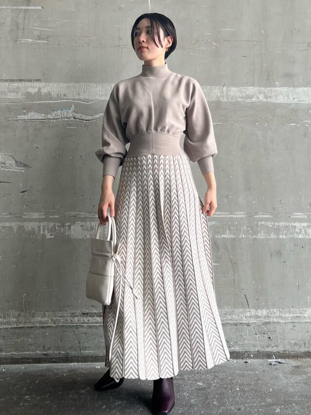 レッド系のブーツ、ベージュ系のワンピース、ホワイト系のハンドバッグを着用したレディースの秋コーディネートの6枚目の写真