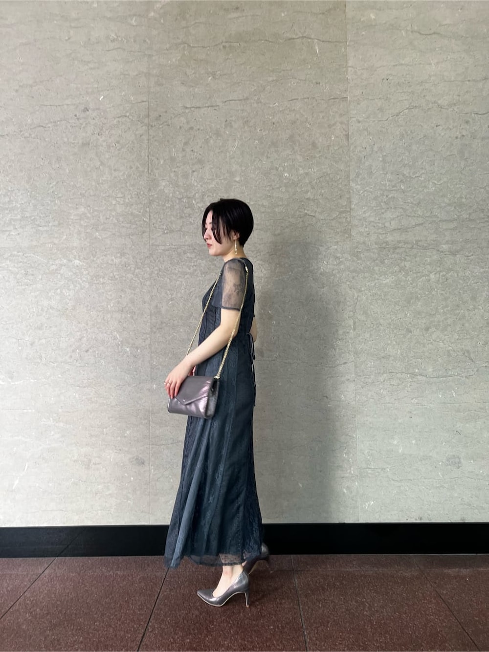 シルバー系のパンプス、グレー系のドレス、シルバー系のクラッチバッグを着用したレディースの冬コーディネートの2枚目の写真