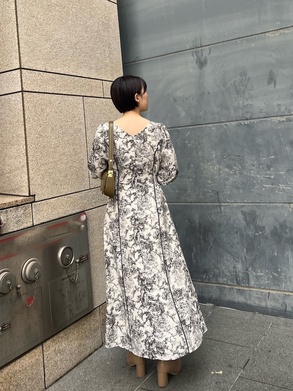 ホワイト系のノーカラーコート、ホワイト系のワンピース、ベージュ系のブーツを着用したレディースの冬コーディネートの3枚目の写真