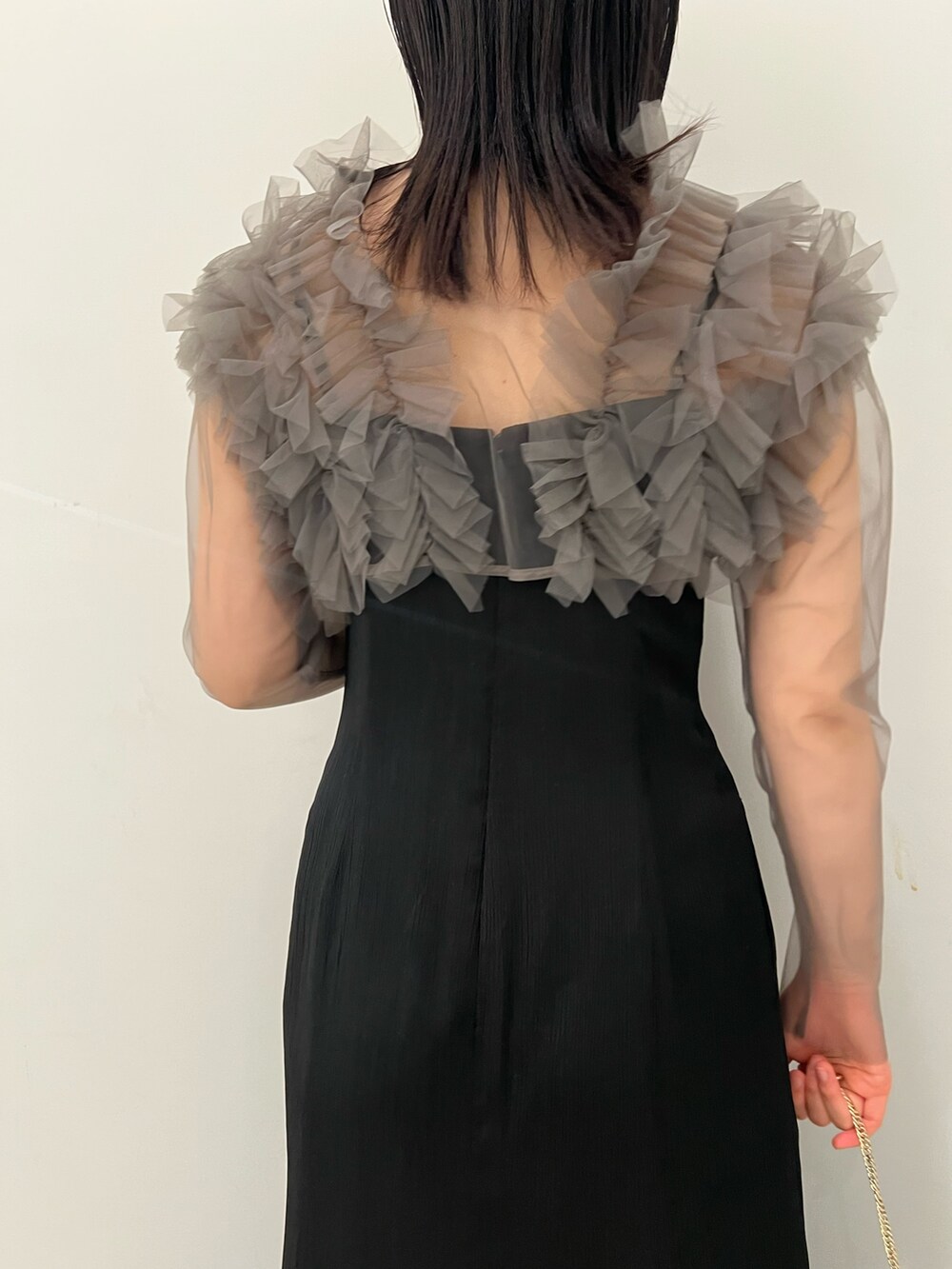 グレー系のドレス、ゴールド系のクラッチバッグ、ゴールド系のパンプスを着用したレディースの春コーディネートの5枚目の写真