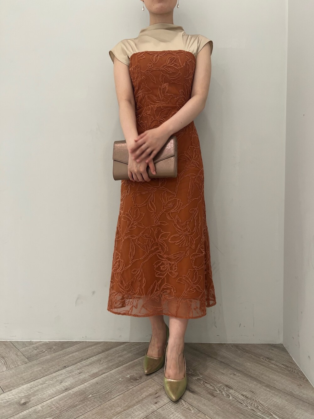 ゴールド系のパンプス、ゴールド系のハンドバッグ、オレンジ系のドレスを着用したレディースの夏コーディネートの6枚目の写真