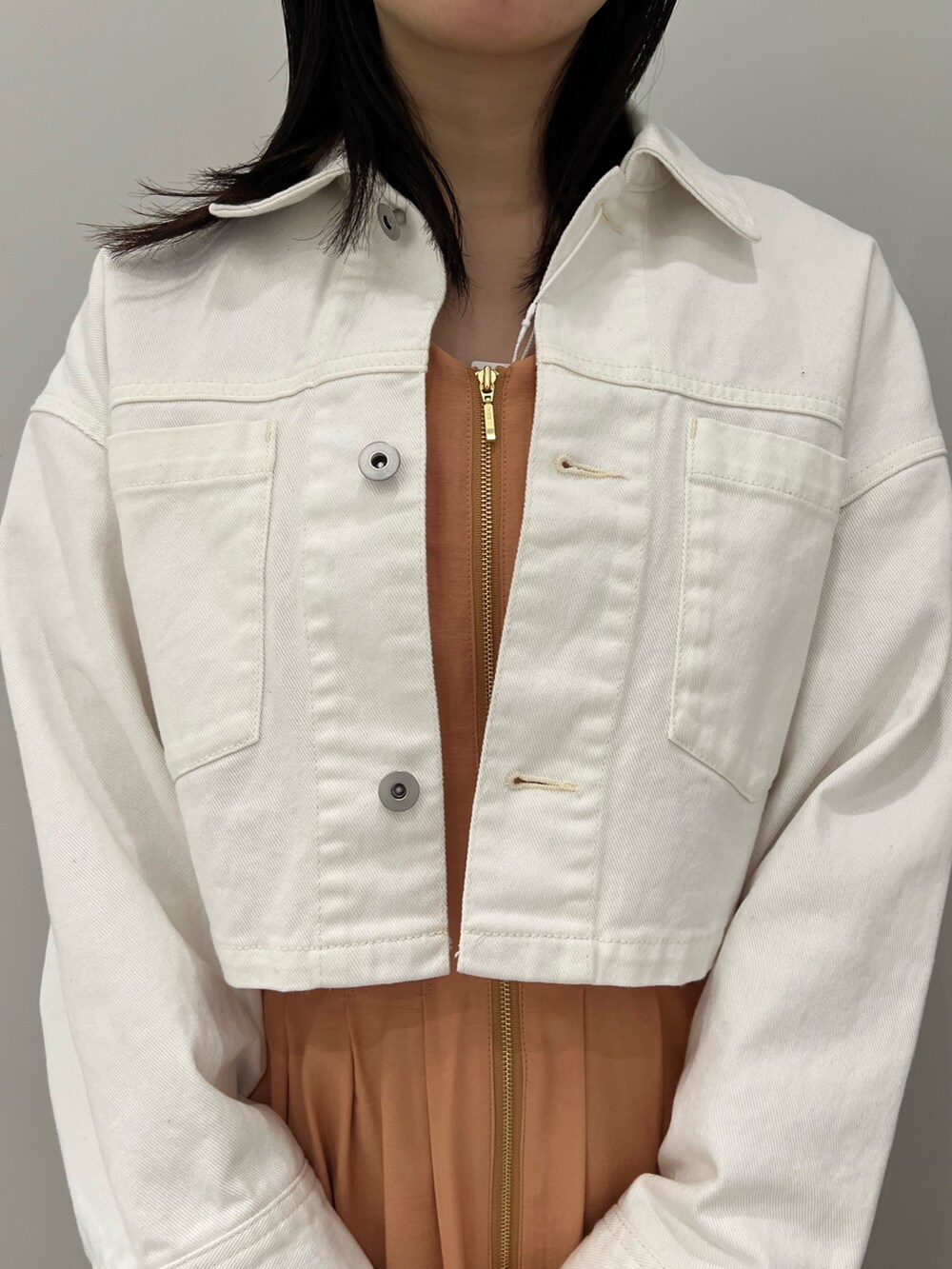 ホワイト系のサンダル、オレンジ系のワンピース、ホワイト系のデニムジャケットを着用したレディースの春コーディネートの3枚目の写真