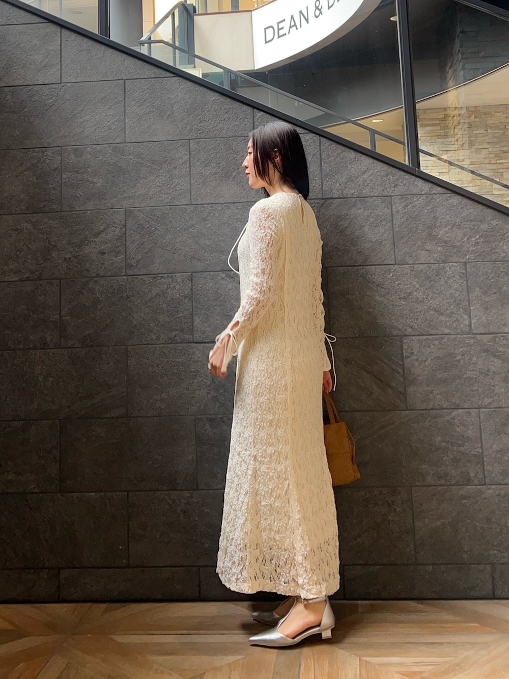 ホワイト系のワンピース、ブラウン系のハンドバッグ、シルバー系のパンプスを着用したレディースの冬コーディネートの2枚目の写真