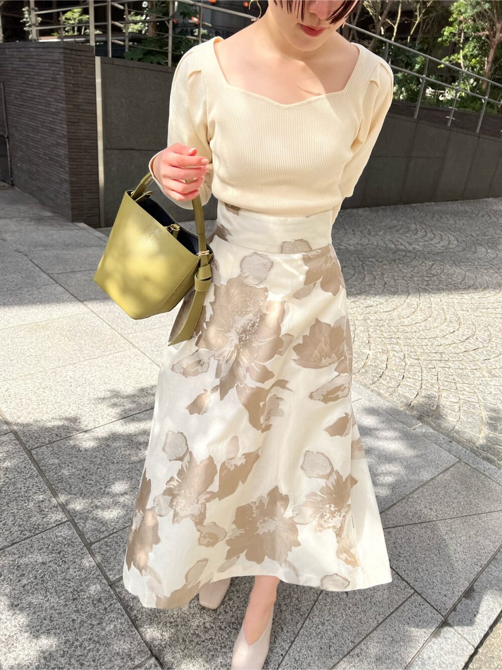 イエロー系のその他アウター、ベージュ系のスカート、ホワイト系のニット/セーターを着用したレディースの冬コーディネートの2枚目の写真