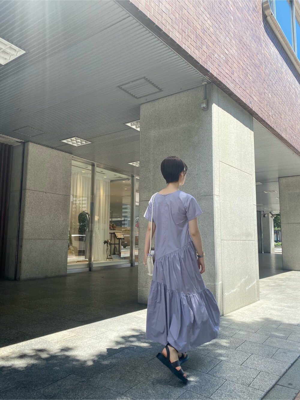 ブラウン系のサンダル、ホワイト系のショルダーバッグ、パープル系のワンピースを着用したレディースの夏コーディネートの2枚目の写真