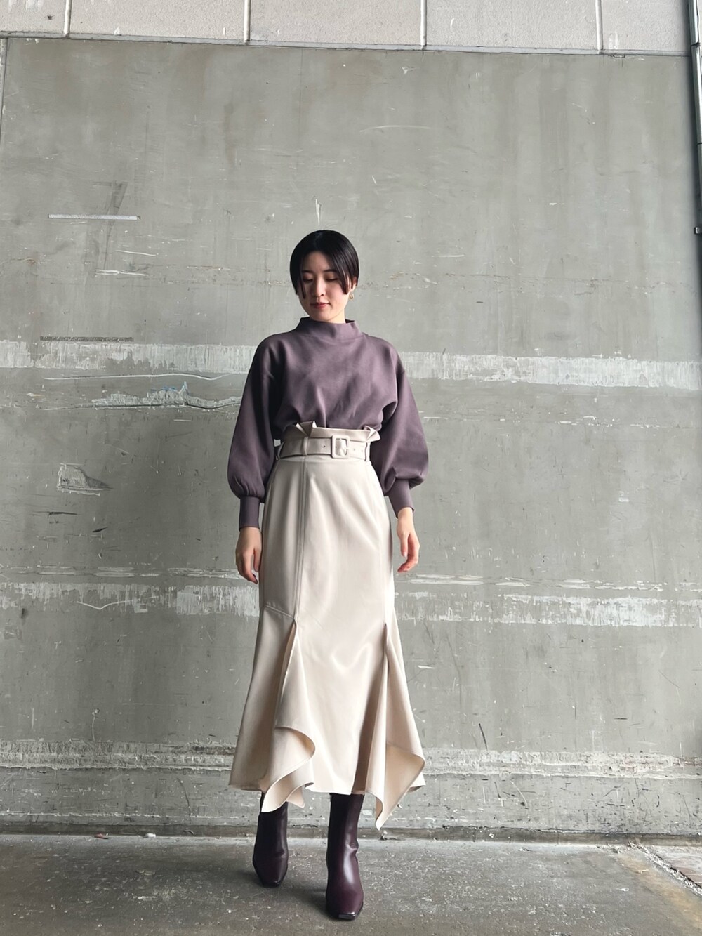 ホワイト系のノーカラーコート、ベージュ系のニット/セーター、ブラウン系のスカートを着用したレディースの秋コーディネートの4枚目の写真