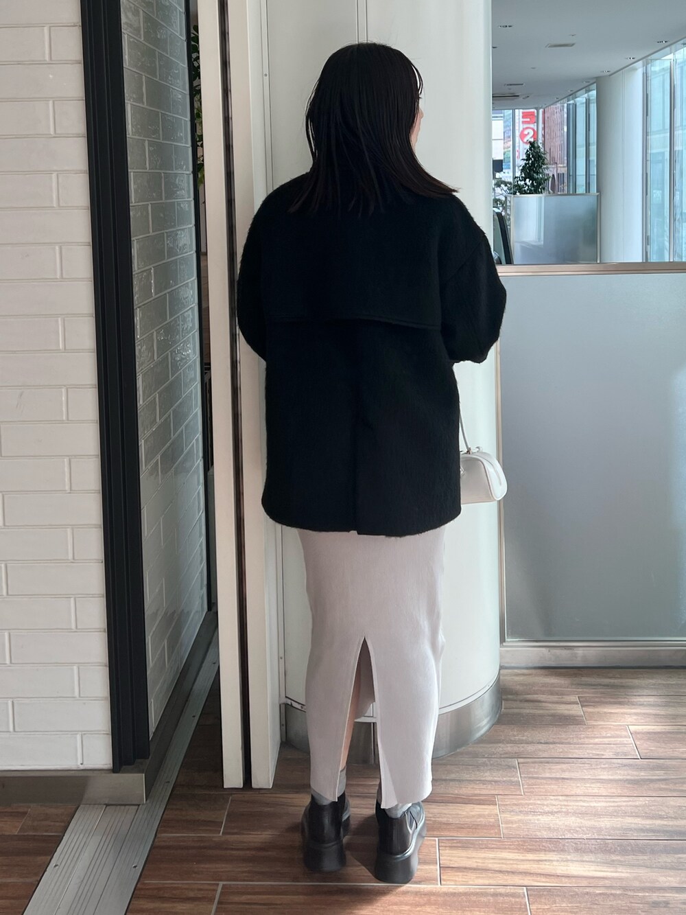 ブラック系のステンカラーコート、ブルー系のワンピース、ブラック系のブーツを着用したレディースの冬コーディネートの3枚目の写真