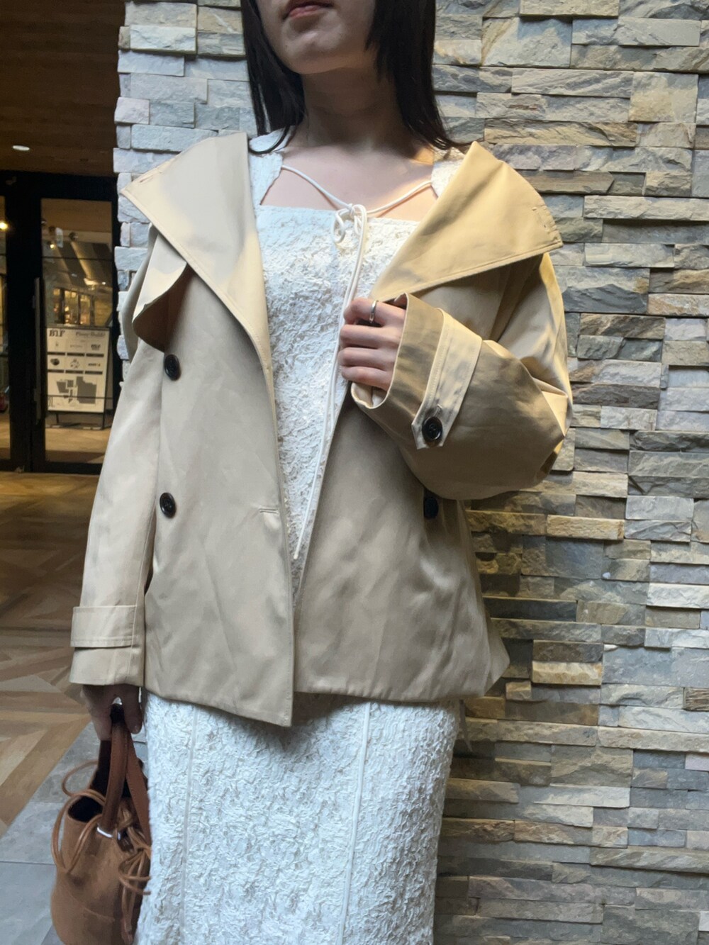 ブラウン系のハンドバッグ、ホワイト系のワンピース、ベージュ系のトレンチコートを着用したレディースの冬コーディネートの4枚目の写真