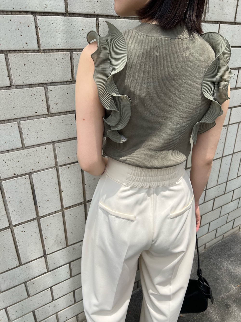 グリーン系のニット/セーター、ホワイト系のその他パンツ、ブラック系のサンダルを着用したレディースの春コーディネートの4枚目の写真