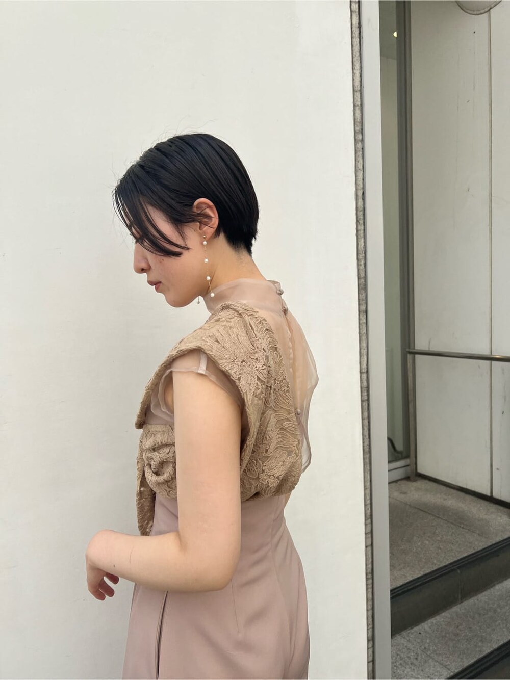 ゴールド系のクラッチバッグ、ベージュ系のパンツドレス、ブラック系のその他トップスを着用したレディースの夏コーディネートの9枚目の写真
