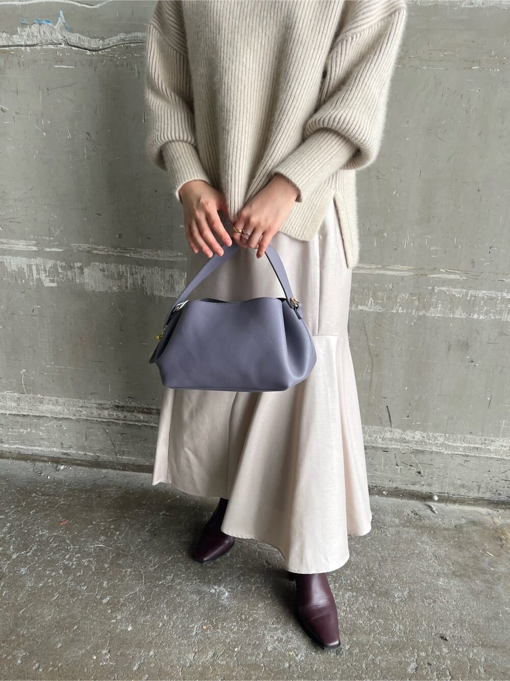 レッド系のブーツ、グレー系のスカート、パープル系のハンドバッグを着用したレディースの秋コーディネートの8枚目の写真